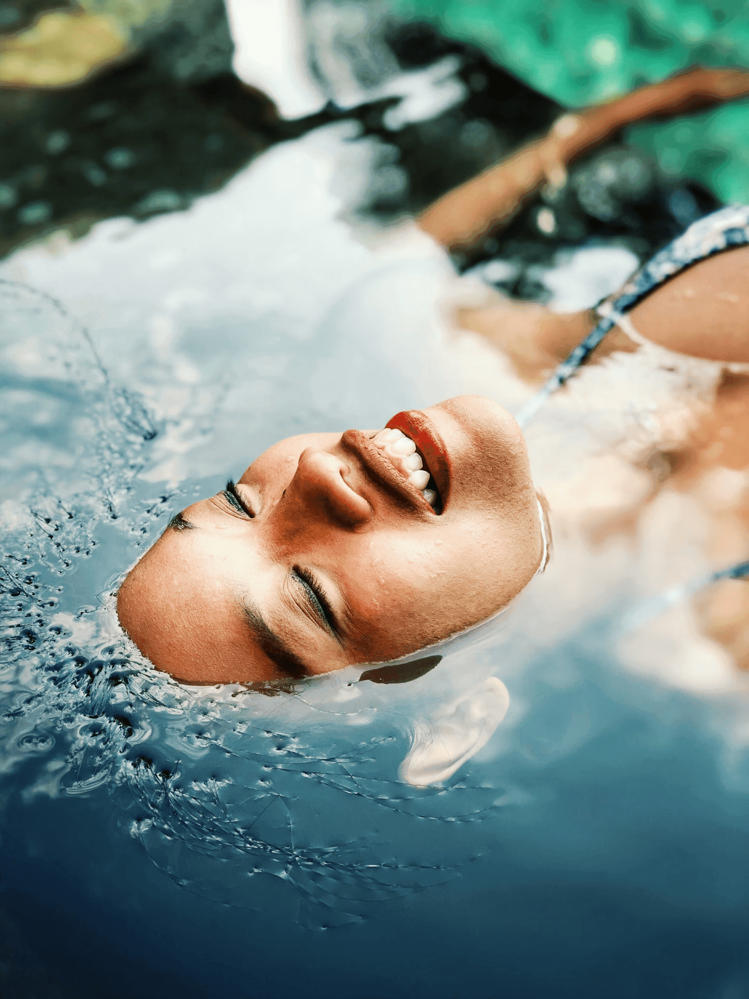 Mujer sonriente en agua, piel revitalizada. Fotorejuvenecimiento iderma: rejuvenece tu piel en Murcia, Alicante y Orihuela. Tratamiento no invasivo para un aspecto fresco y radiante.